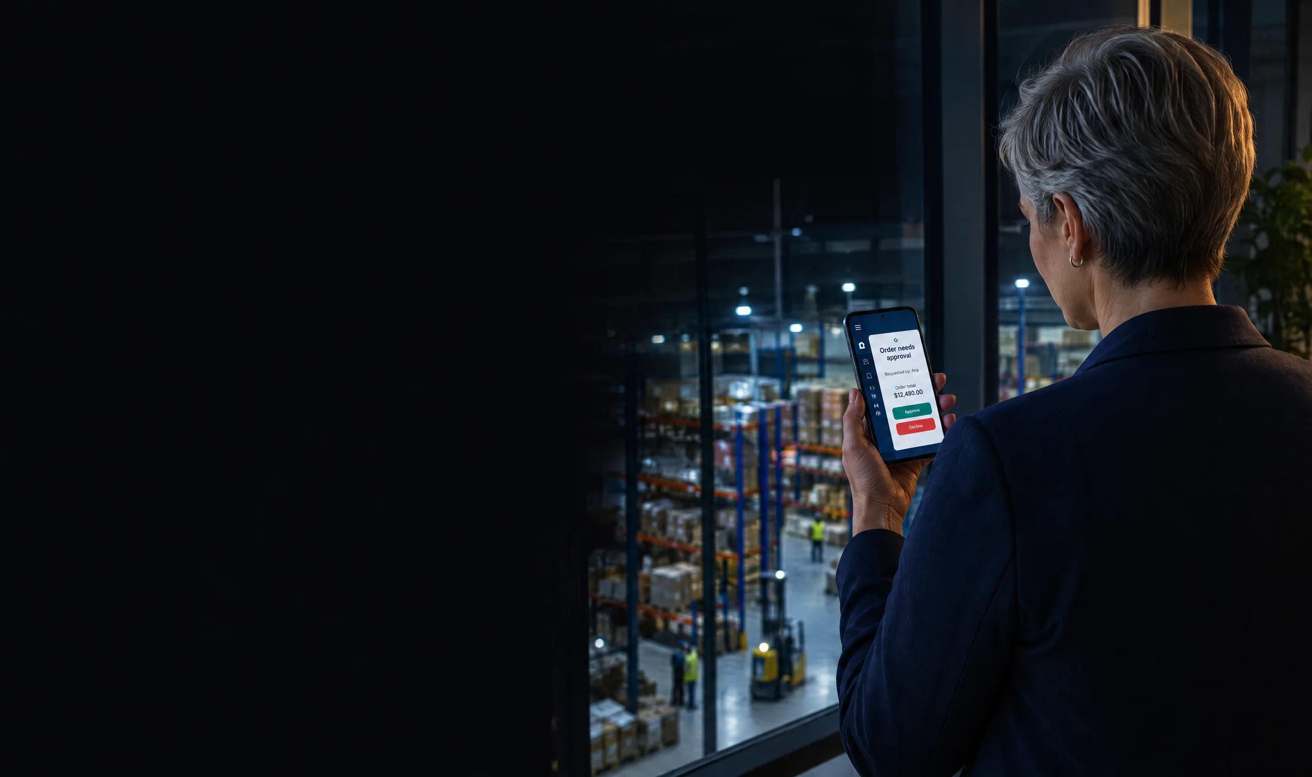 Operations director approves a team order from her phone at a quiet warehouse office window Operations director approves a team order from her phone at a quiet warehouse office window