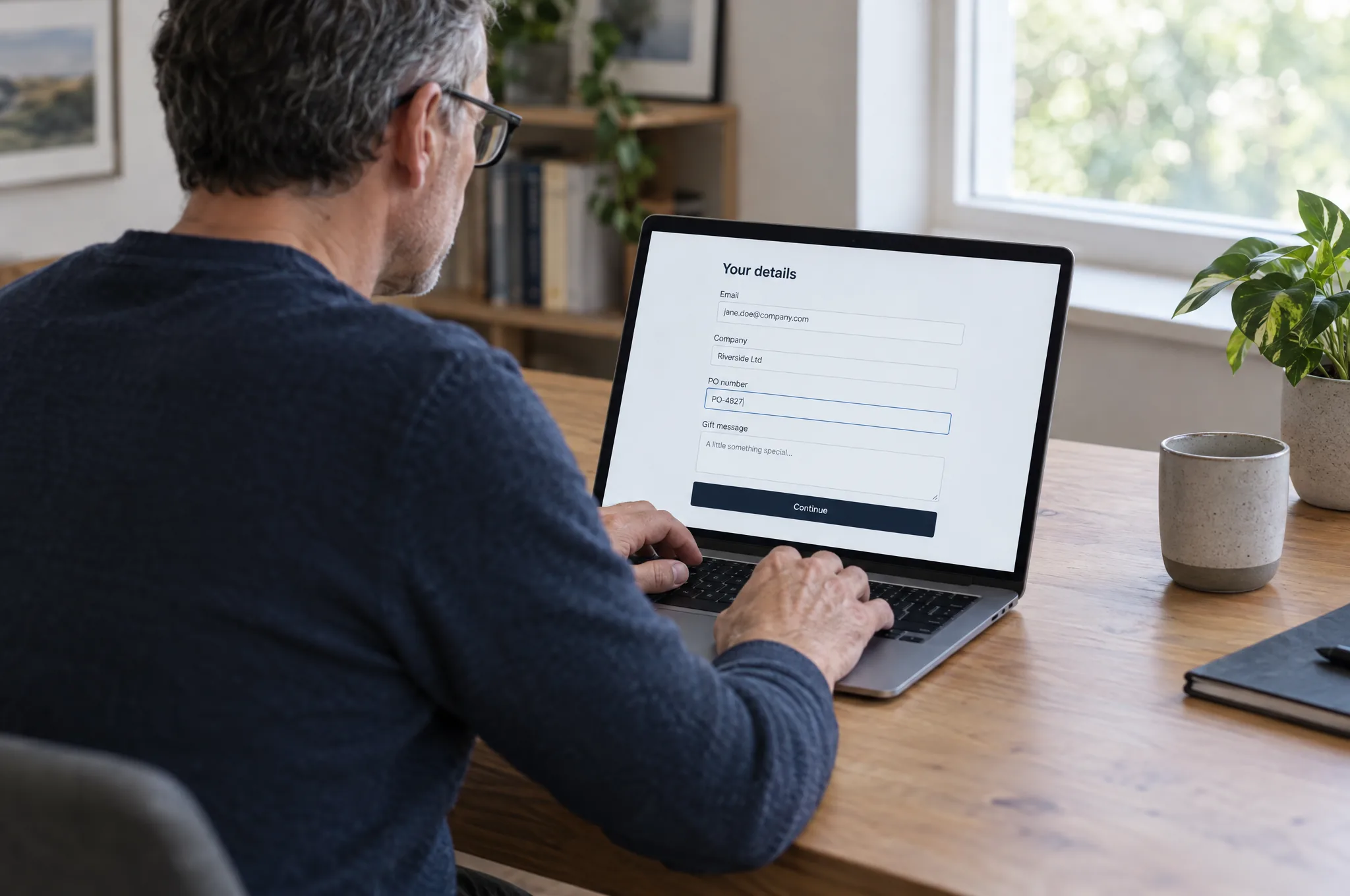 A business buyer types a PO number into custom checkout fields on his laptop A business buyer types a PO number into custom checkout fields on his laptop