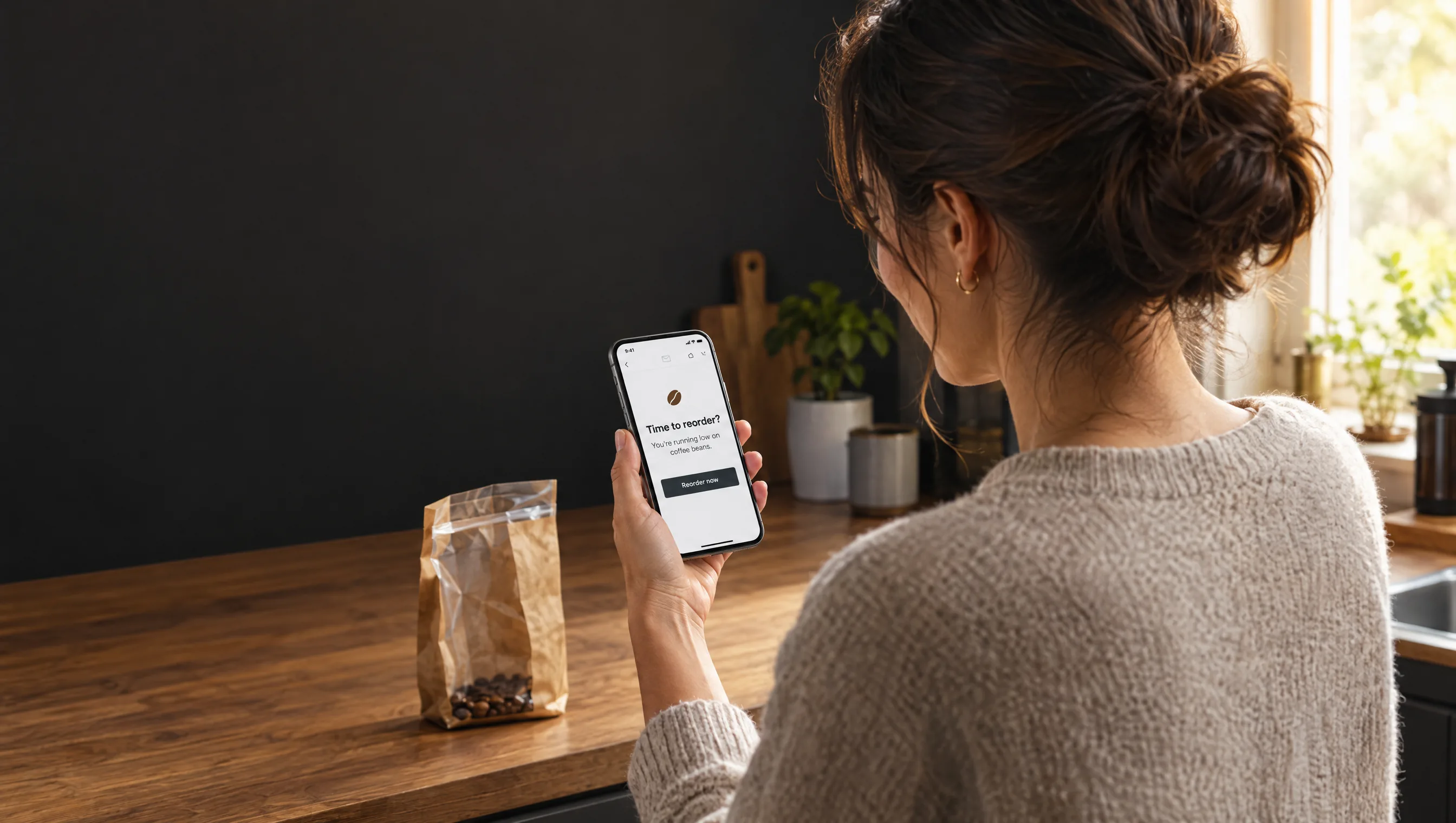 A customer gets a reorder reminder email on her phone as her coffee runs low