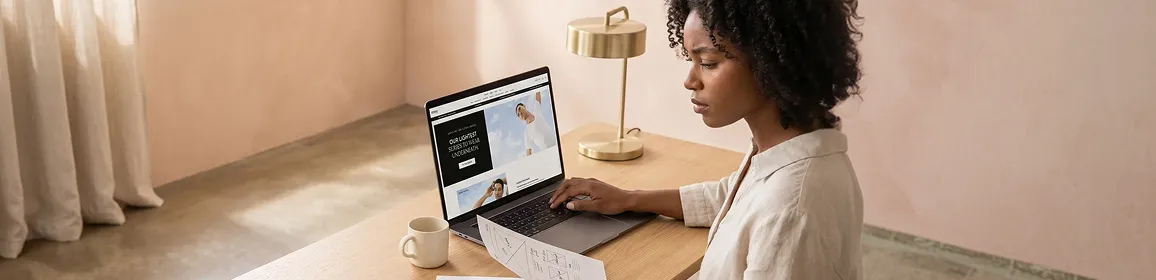 Calm ecommerce merchant reviewing a polished, redesigned Adobe Commerce storefront on laptop, soft peach ambient light Calm ecommerce merchant reviewing a polished, redesigned Adobe Commerce storefront on laptop, soft peach ambient light
