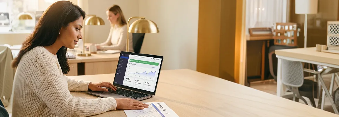 Ecommerce merchant reviewing store migration plan on laptop in bright modern office Ecommerce merchant reviewing store migration plan on laptop in bright modern office
