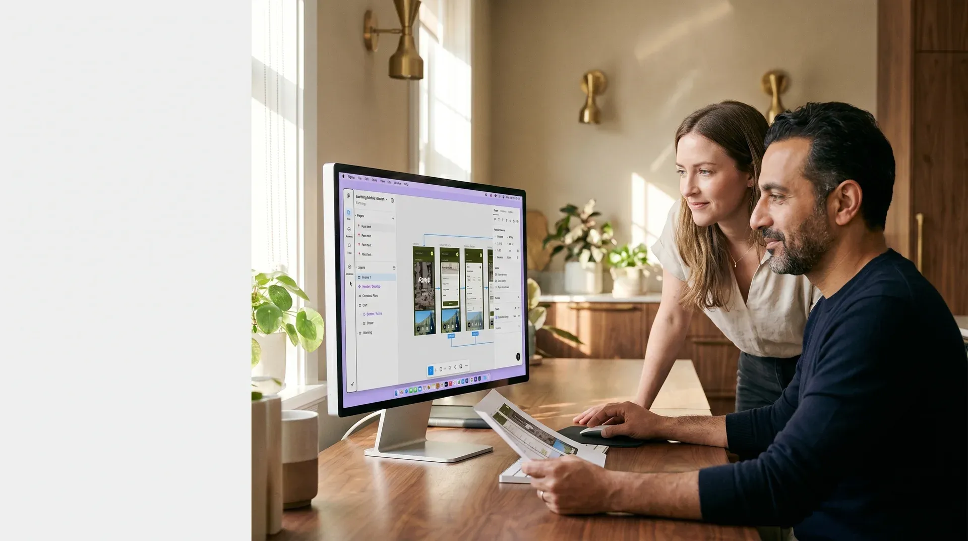 User experience designer and project stakeholder reviewing design mockup screens side by side at a desk with morning window light and engaged focus User experience designer and project stakeholder reviewing design mockup screens side by side at a desk with morning window light and engaged focus