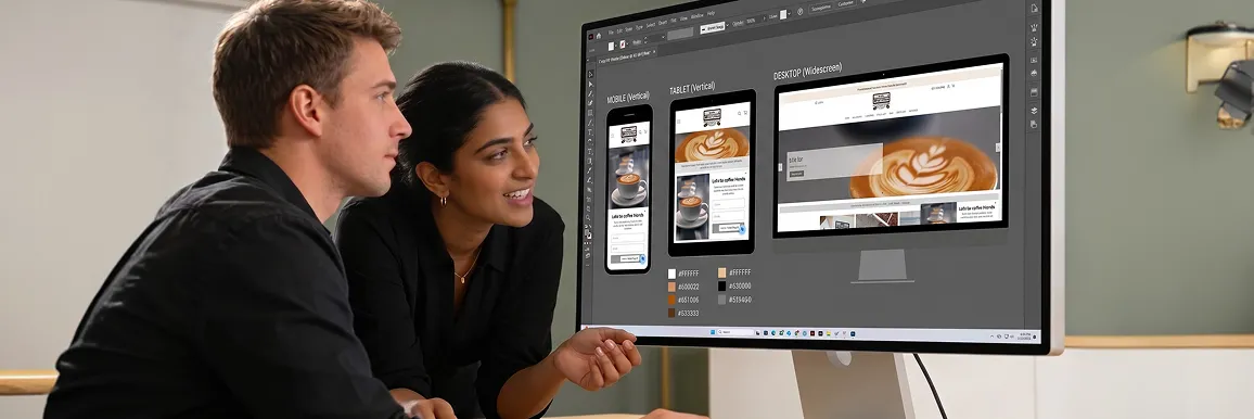 Developer and designer reviewing responsive breakpoint artboards of a website in Figma on a monitor at a bright studio desk Developer and designer reviewing responsive breakpoint artboards of a website in Figma on a monitor at a bright studio desk