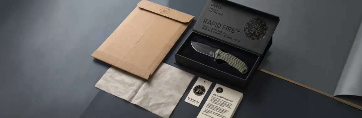 Off Grid Knives premium product packaging system showing black magnetic presentation box, branded kraft mailer, patterned tissue paper, hang tag, and insert card laid flat on a smoky charcoal surface in studio light Off Grid Knives premium product packaging system showing black magnetic presentation box, branded kraft mailer, patterned tissue paper, hang tag, and insert card laid flat on a smoky charcoal surface in studio light