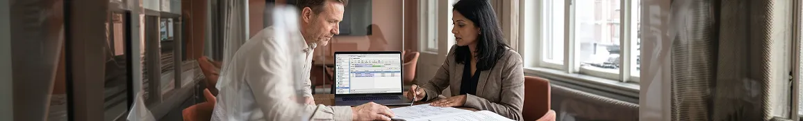 Senior software architect in focused discussion with client reviewing industry-specific software architecture proposal with natural meeting room light from side angle Senior software architect in focused discussion with client reviewing industry-specific software architecture proposal with natural meeting room light from side angle