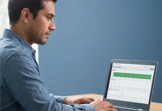 Engineer at a laptop reviewing a stabilized all-green monitoring dashboard showing the rescued legacy application now healthy in bright daylight Engineer at a laptop reviewing a stabilized all-green monitoring dashboard showing the rescued legacy application now healthy in bright daylight