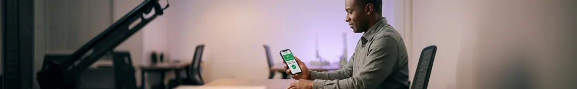 Technical founder at a desk holding a phone showing a green P1 Resolved incident notification with a 34-minute resolution, calm relieved side profile in warm lamp light Technical founder at a desk holding a phone showing a green P1 Resolved incident notification with a 34-minute resolution, calm relieved side profile in warm lamp light