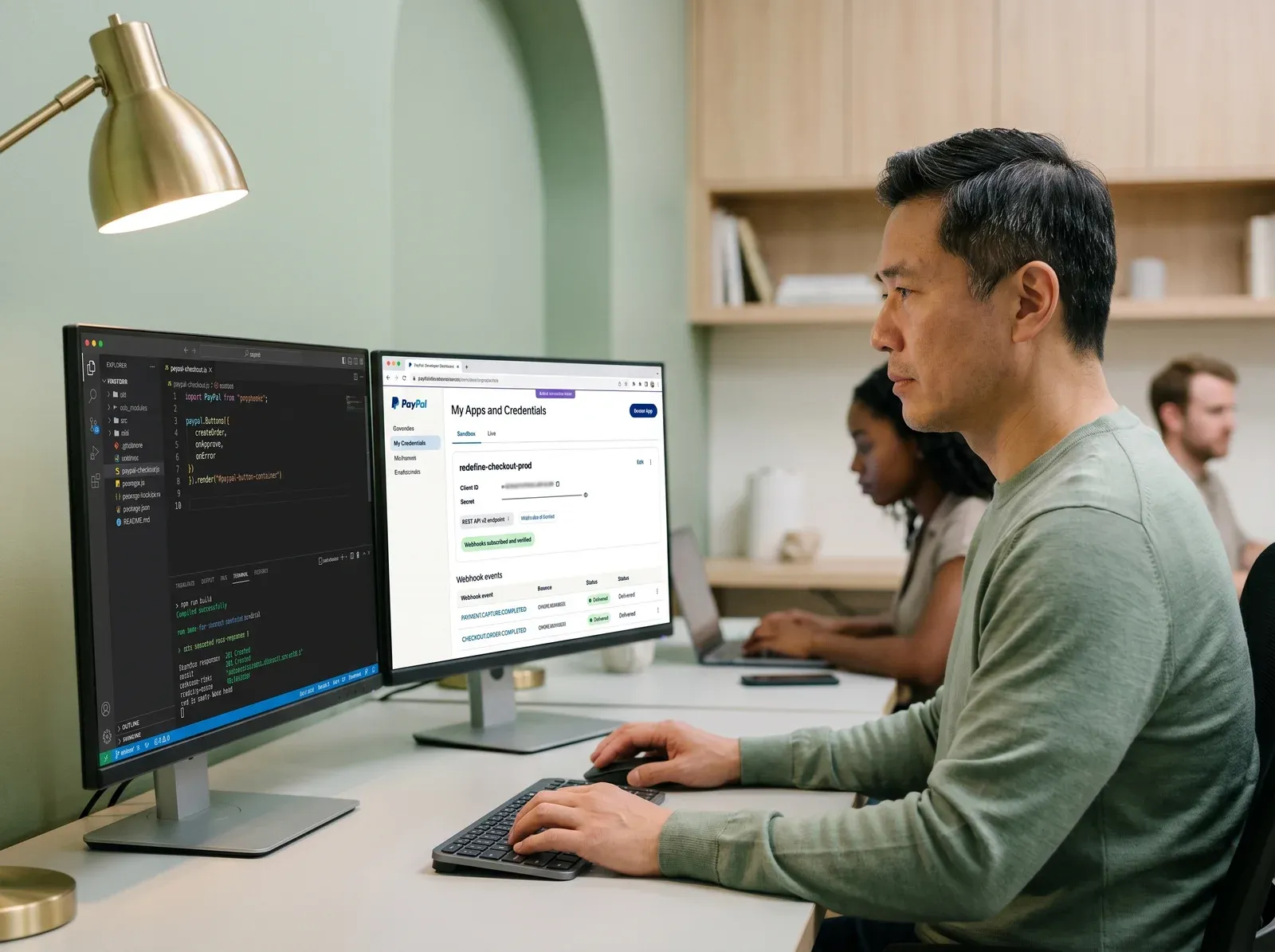 Developer configuring PayPal REST API integration on dual monitors Developer configuring PayPal REST API integration on dual monitors