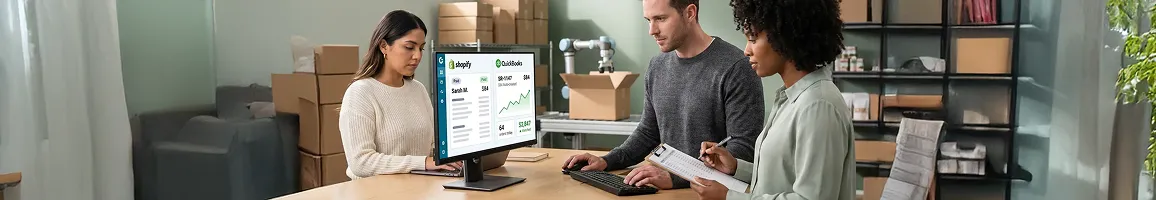 Shopify store operations team packing orders and checking automated QuickBooks accounting reports, natural warehouse light Shopify store operations team packing orders and checking automated QuickBooks accounting reports, natural warehouse light