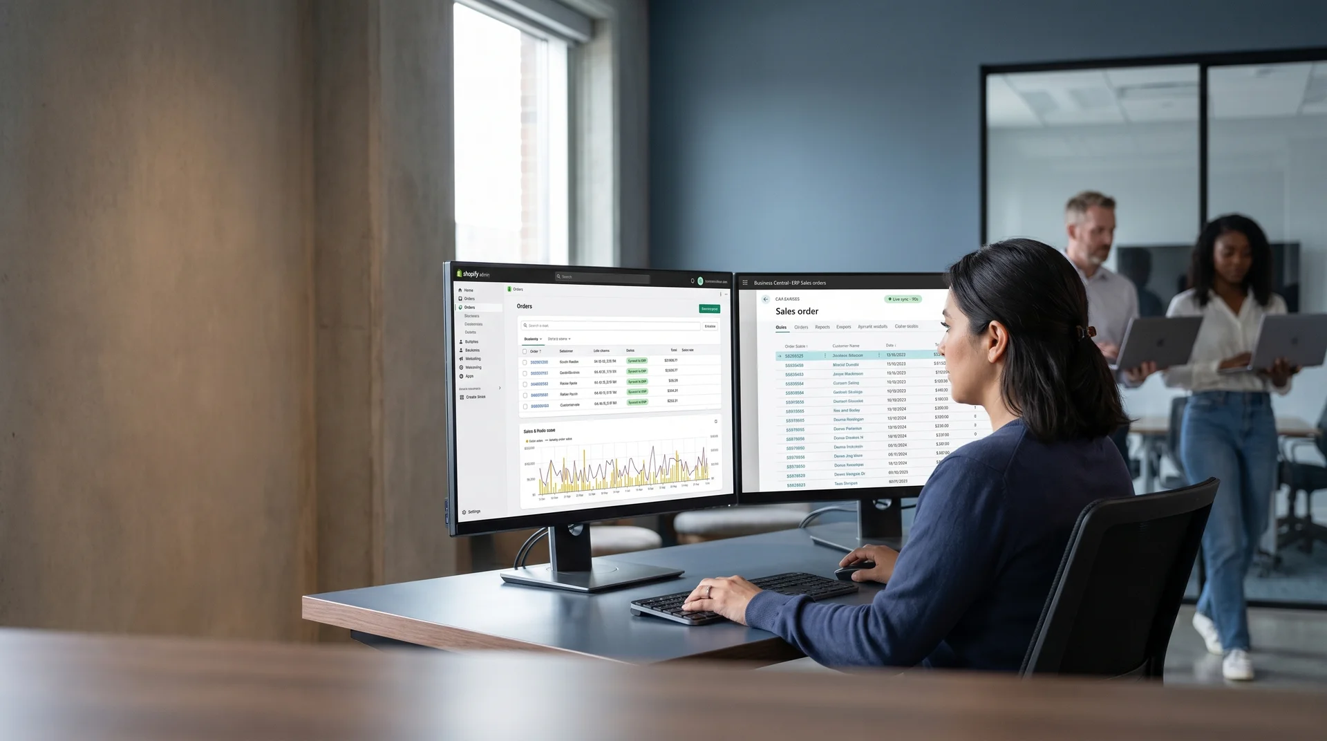 Ecommerce operations manager at dual monitors showing live Shopify and enterprise resource planning data synchronized in real time Ecommerce operations manager at dual monitors showing live Shopify and enterprise resource planning data synchronized in real time