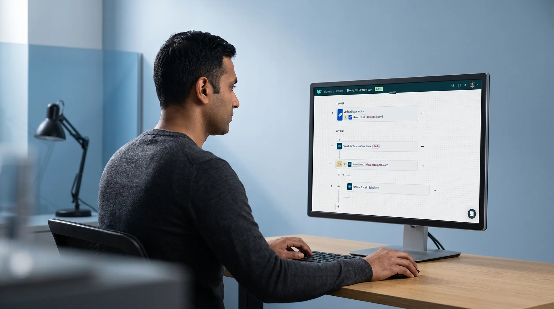 Integration engineer reviewing a Workato recipe diagram on a large monitor showing connected application nodes and automated workflow logic Integration engineer reviewing a Workato recipe diagram on a large monitor showing connected application nodes and automated workflow logic