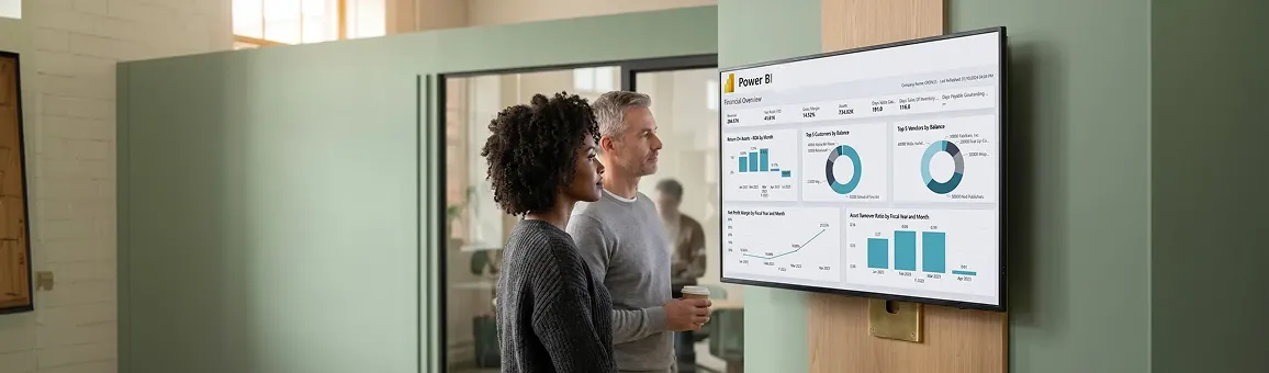 Leadership team reviewing a live Power BI report on a wide monitor Leadership team reviewing a live Power BI report on a wide monitor