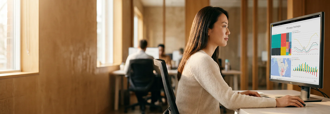 Business intelligence analyst reviewing Power BI executive dashboards on a large monitor in a naturally lit modern office Business intelligence analyst reviewing Power BI executive dashboards on a large monitor in a naturally lit modern office