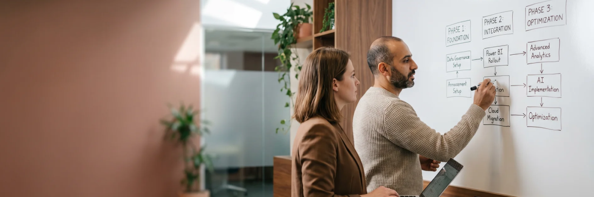 Two Power BI strategy consultants reviewing a data roadmap on a whiteboard in a modern workspace Two Power BI strategy consultants reviewing a data roadmap on a whiteboard in a modern workspace