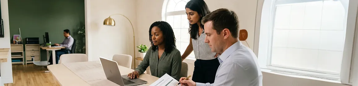 Healthcare administrative team at desks reviewing documents and screens, institutional light, wide angle Healthcare administrative team at desks reviewing documents and screens, institutional light, wide angle