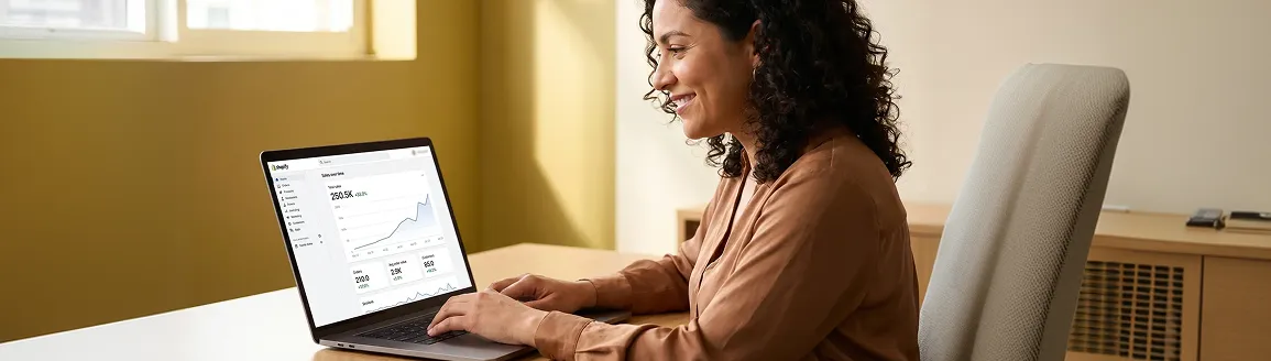 Merchant smiling at her laptop reviewing strong revenue results after launching a custom Shopify app Merchant smiling at her laptop reviewing strong revenue results after launching a custom Shopify app
