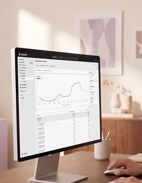 Fashion brand founder reviewing Shopify store analytics in design studio Fashion brand founder reviewing Shopify store analytics in design studio